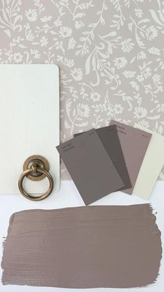 some paint swatches are sitting on a table next to a wall paper and a ring