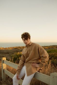 a man sitting on a wooden fence near the ocean