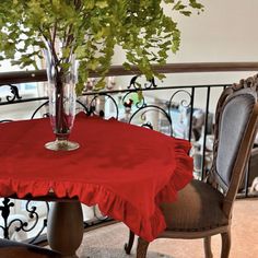 a table with a red cloth on it next to a glass vase filled with flowers