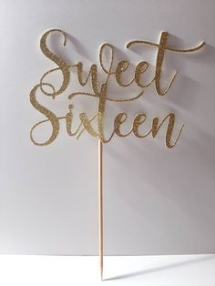 a gold cake topper that says sweet sixteen on it's wooden stick in front of a white background