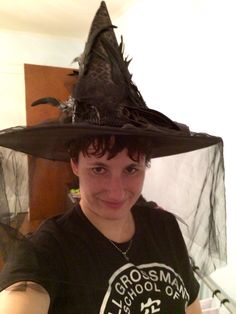 a woman wearing a witches hat and posing for the camera with her hand on her hip