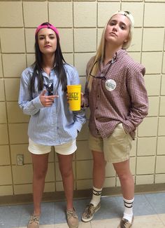 two young women standing next to each other in front of a wall holding coffee mugs