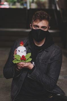 a man wearing a black mask holding a stuffed animal