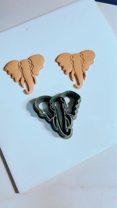 two cookie cutters sitting next to each other on top of a white board with brown and black designs