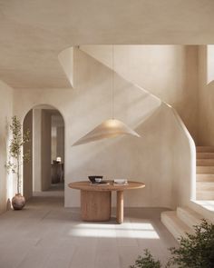 a dining room with a table and stairs in the back ground, next to potted plants