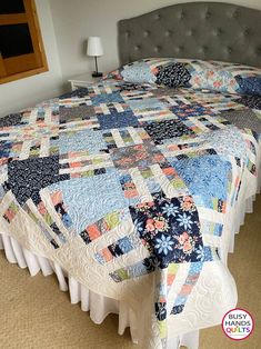 a bed with a blue and white quilt on it's headboard in a bedroom