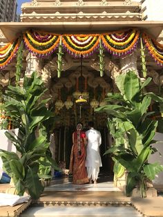 a man and woman are standing in front of a decorated shrine with flowers on it