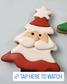 a santa clause cookie next to a green shoe on top of a gray surface with the caption tap here to watch