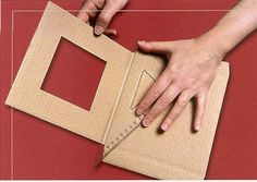 a person cutting out a square with a ruler on top of it and another piece of cardboard in front of them