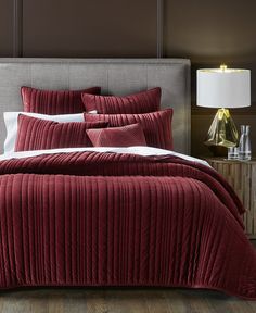 a bed with red bedspread and pillows in a bedroom