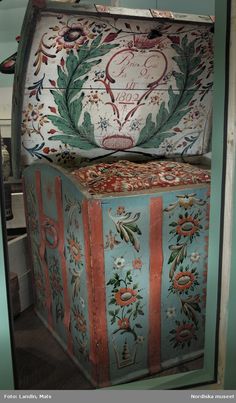 an old painted chest sitting on top of a wooden floor