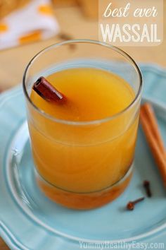 three glasses filled with apple cider on top of a wooden tray next to apples