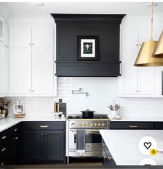 a kitchen with black and white cabinets, gold accents and brass pendant lights over the stove