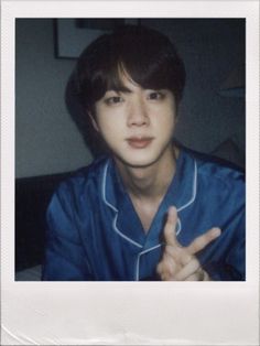 a young man is making the peace sign with his hand while sitting in front of a flower