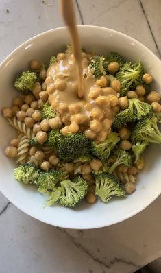 a white bowl filled with broccoli and chickpeas covered in gravy