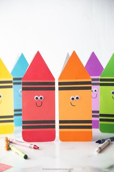 colorful crayons with faces drawn on them are lined up next to markers and pencils