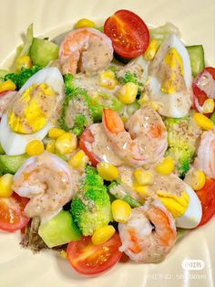 a salad with shrimp, broccoli, corn and tomatoes is shown on a white plate