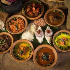 many different types of food are in bowls on a table with rice and other foods