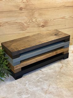 two wooden boxes sitting next to each other on top of a marble counter with a plant