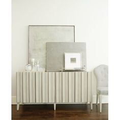 a white chair sitting in front of a mirror on top of a wooden floor next to a dresser