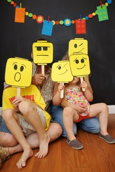 two children and an adult sitting on the floor with paper cutouts in front of them