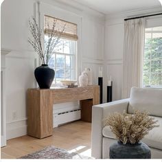 a living room filled with furniture and a vase on top of a wooden table next to a window