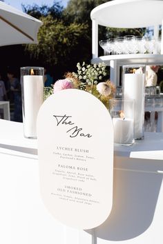 a table with candles, flowers and menus on it for an outdoor wedding ceremony