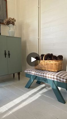 a bench with a basket on top of it in front of a cabinet and wall