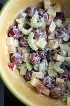 a yellow bowl filled with grapes and cheese