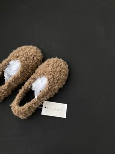 a pair of brown slippers sitting on top of a black floor next to a white tag