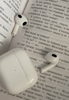 two apple airpods sitting on top of an open book