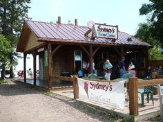 people are standing in front of a small building with a sign that says sydney's on it