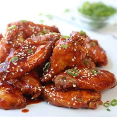 a white plate topped with chicken wings covered in sesame seeds