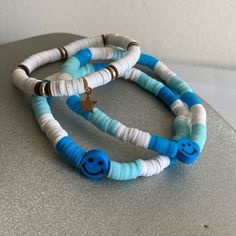 two blue and white bracelets with smiley face beads on each one, sitting on top of a table