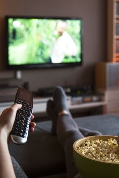 a person holding a cell phone in front of a television with a bowl of cereal