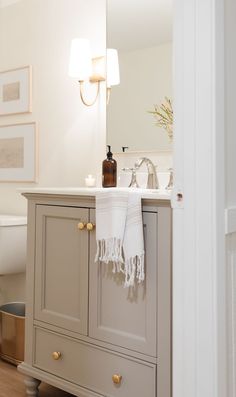 a bathroom with a sink, mirror and towel hanging on the cabinet doors in front of it