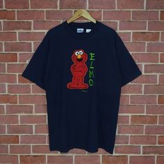 an elmo t - shirt hanging on a brick wall