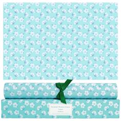 the wrapping paper is blue and has white flowers on it, with a green ribbon