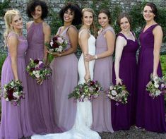 a group of women standing next to each other in long purple dresses and holding bouquets