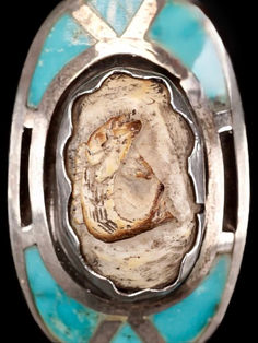 a silver and turquoise stone ring with an image on the center, inlaid to it