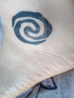 a person's foot with a small tattoo on the side of their leg, which has a spiral design