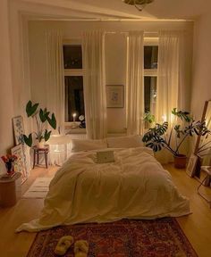 a bed sitting in a bedroom under a window next to a rug on top of a hard wood floor