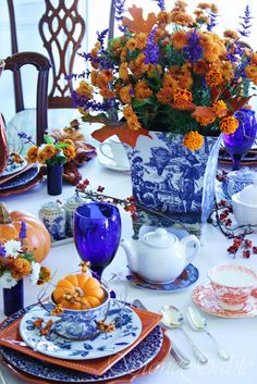 a blue and white vase filled with orange flowers on top of a dining room table