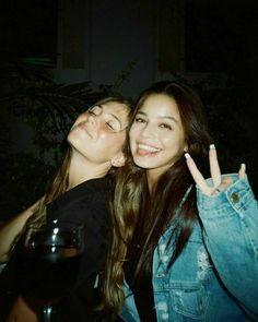 two women posing for the camera with their fingers in the air