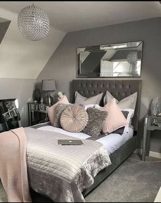 a bedroom with grey walls and white bedding, mirrored nightstands and mirror on the wall