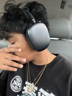 a young man wearing headphones while sitting in a car with his hand on his face