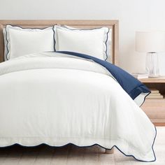 a white bed with blue trim and pillows