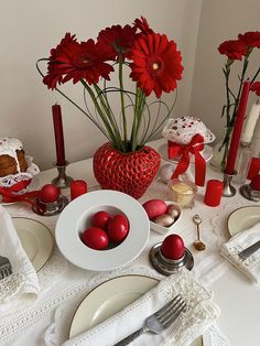 the table is set with red candles and plates