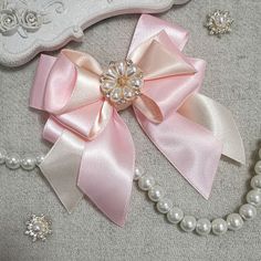 a close up of a necklace with pearls and a bow