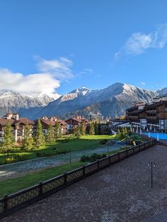 the mountains are covered with snow in the distance, and there is a pool surrounded by grass